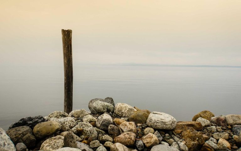 Smooth stones on a calm shoreline at golden hour, placeholder hero image