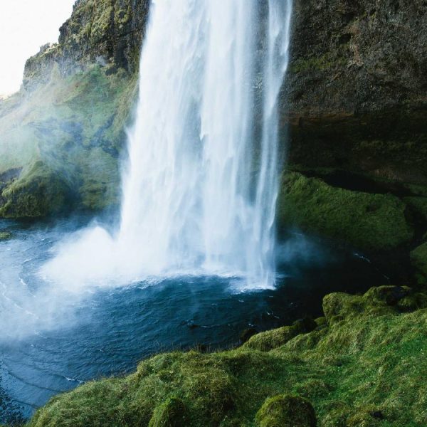 A powerful waterfall flowing through green rock, symbolic of energy and flow
