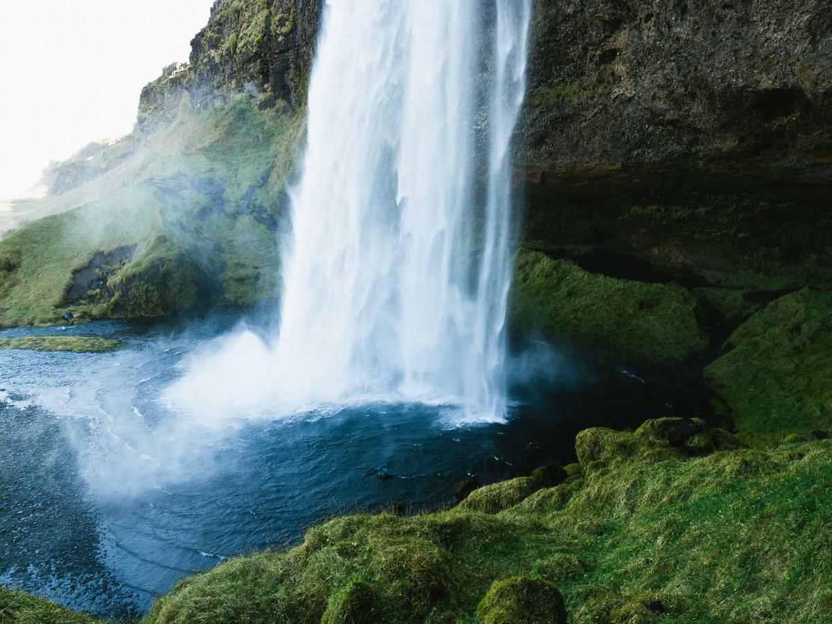 A powerful waterfall flowing through green rock, symbolic of energy and flow